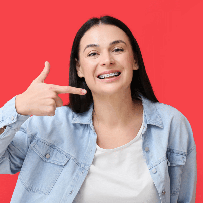 Develop self-esteem with orthodontic treatment 3 Girl smiling and pointing toward her brand new smile, representing self-esteem