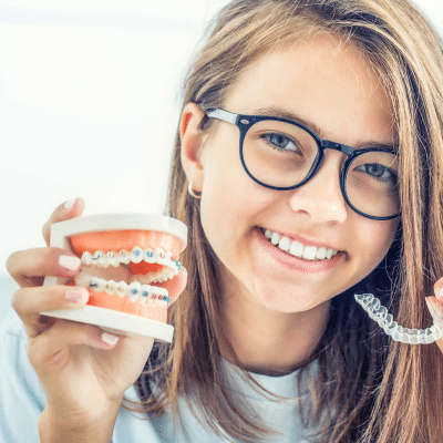 Navigating foods with braces or aligners 3 Young girl smiling holding aligners and plastic teeth