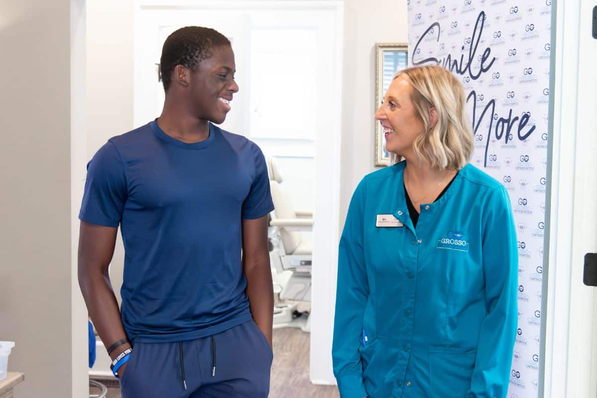 Patient and dental hygienist smiling at each other while walking through the hallway at grosso orthodontics in south carolina
