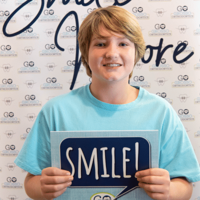 Step‑by‑step guide: how to clean braces properly 3 Kid holding a sign that says 'smile! ', representing how to clean braces