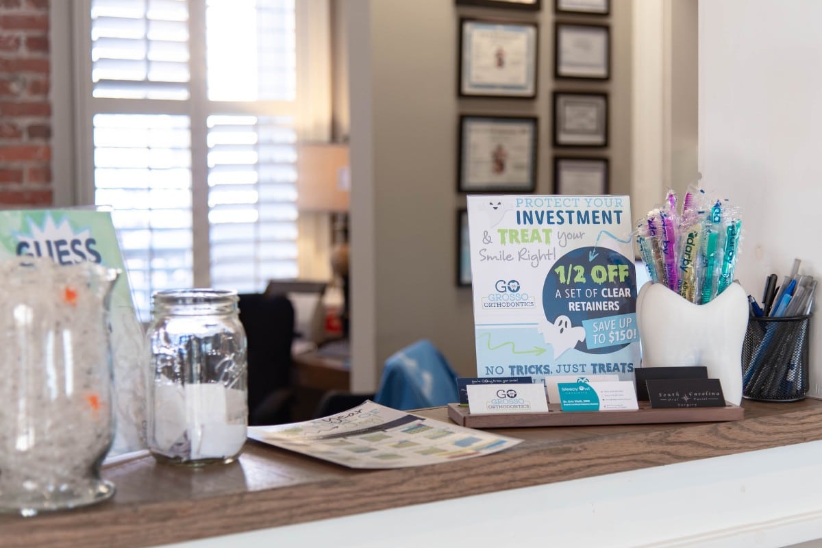 Grosso-orthodontics-georgetown-front-desk Front desk display at grosso orthodontics in georgetown, sc with retainer and patient care information.